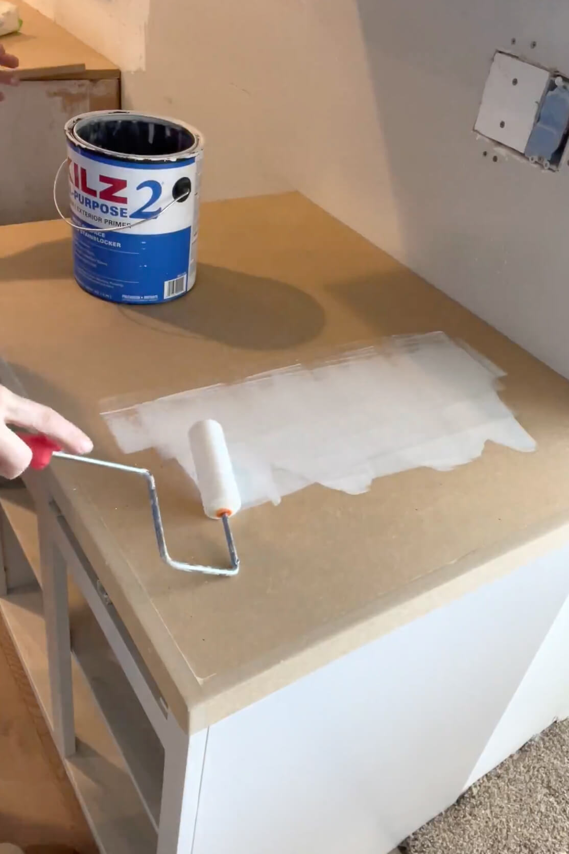 Priming a countertop as the first step for a faux marble finish.